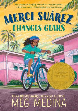 Merci Suarez changes gears blue and green letters across yellow sky palm trees in corners pink buildins young girl with brown hair and blue top and shorts riding blue bicycle on street