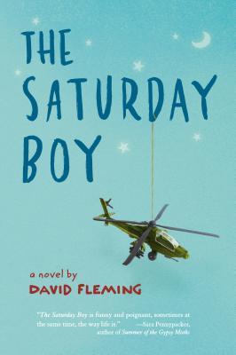The Saturday Boy in dark blue letters across light blue background. stars and crescent moon in white above letters. army helicopter hanging from D in Saturday.