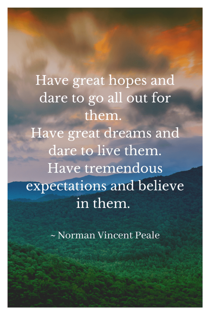 background image of mountains and evening sky with clouds in grey and orange in sky. blue mountains behind forested hillsides. white letters of quote in middle of image. quote says 'Have great hopes and dare to go all out for them. Have great dreams and dare to live them. Have tremendous expectations and believe in them.' by Norman Vincent Peale