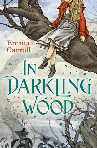 book cover image with white background of old looking trees. Emma Carroll in red letters and In Darkling Wood in blue letters. large tree branch protruding from right of image with image of girl in red coat and silver skirt sitting on branch with her head not visible. images of flowers at bottom edge and blue petals around blue letters.