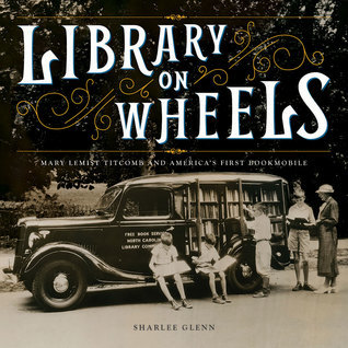 cover image is large black and white image of old fashioned car with bookshelves inside and books on road. group of people standing beside reading and looking for books. large letters in white at top read 'Library on Wheels.'