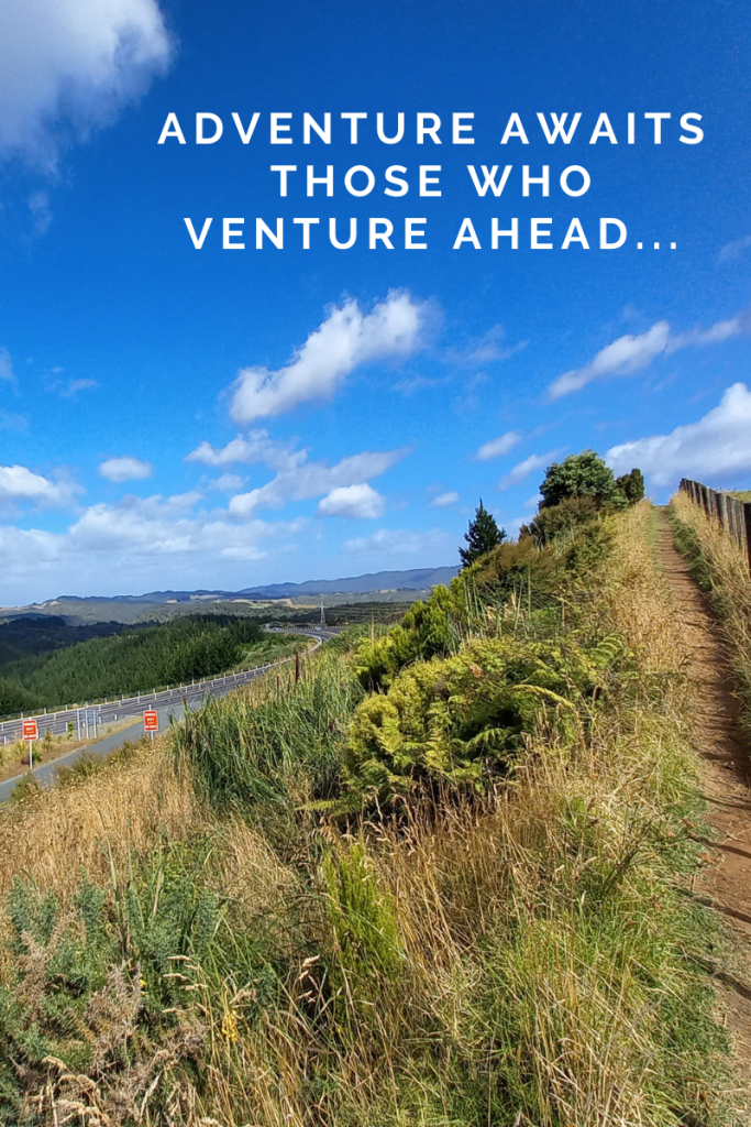 image of green hills and road carving through. blue sky with small clouds. small path and fence on right edge of image. quote in sky in white letters reads Adventure awaits those who venture ahead...