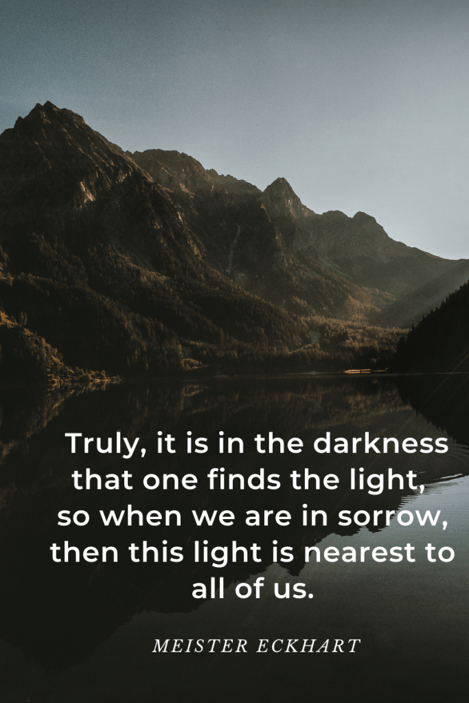 image of mountains and lake in darkened hues. patch of slightly darker sky on top. quote in white letters at bottom over lake. quote reads 'Truly, it is in the darkness that one finds the light, so when we are in sorrow, then this light is nearest to all of us.' Meister Eckhart.