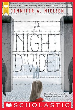 image of what looks like barrier of sorts made of barbed wire in middle between two large walls. young girl at bottom looking through at man and boy on other side. two guards in front of wall parts. large letters created from wire in middle read 'A Night Divided.' red border around with red letters across top reading Jennifer A. Nielsen and Scholastic at bottom.