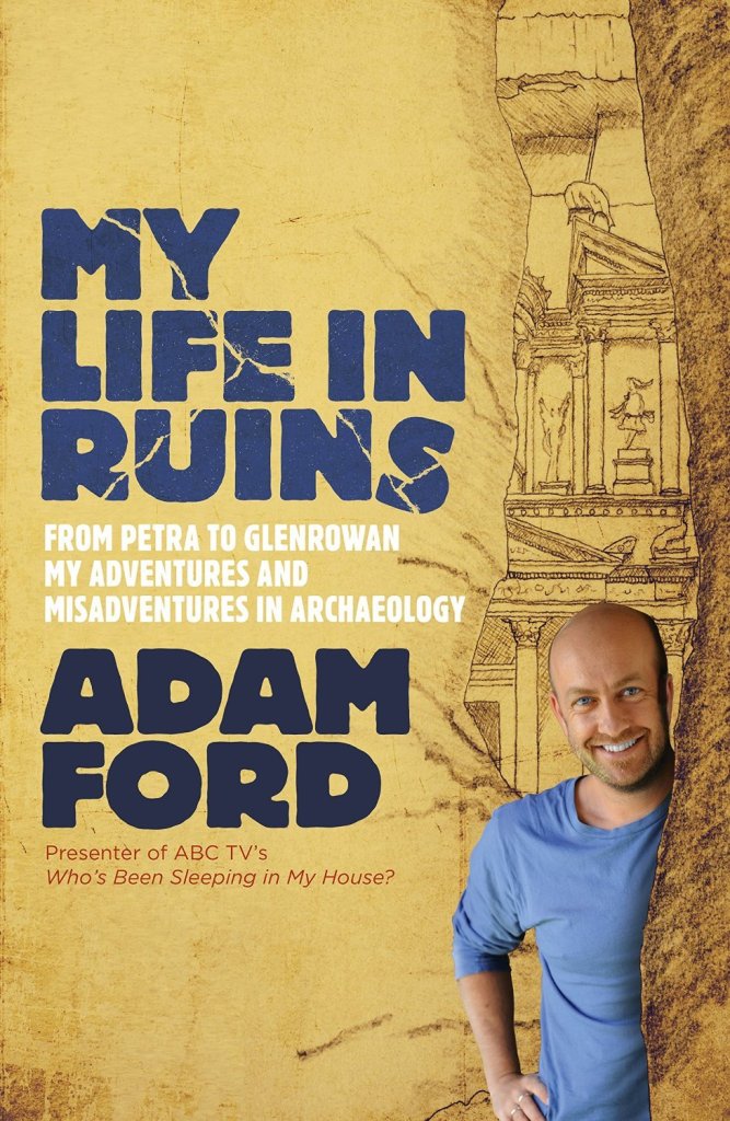 cover image of man with bald head in blue shirt at right bottom edge. hand drawn image of ancient city in light brown and black behind him. large blue letters on left reads My Life in Ruins and darker letters reads Adam Ford.