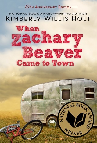 cover image of an old white caravan or trailer on short grass. red bicycle lying on grass beside it. white clouds in sky above. red letters against clouds reads When Zachary Beaver Came to town. gold sticker on side reading National Book Award Winner.