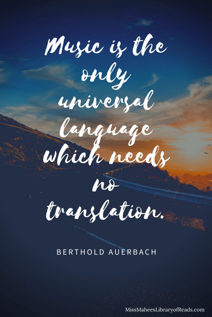 image of road along mountain side with evening sky in middle. orange sun and clouds with dark blue sky above. quote in cursive white letters in middle. quote reads: Music is the only universal language which needs no translation. Berthold Auerbach.