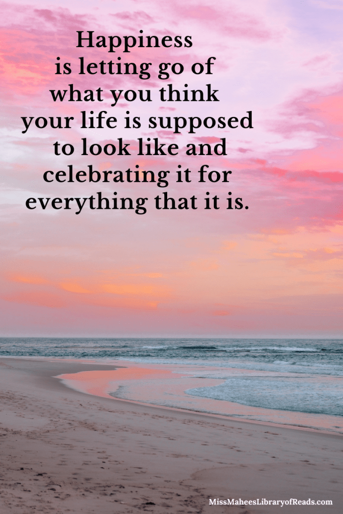 image of beach and sea with pink sky and pink and orange clouds. quote in black letters across top left reads Happiness is letting go of what you think your life is supposed to look like and celebrating it for everything that it is.
