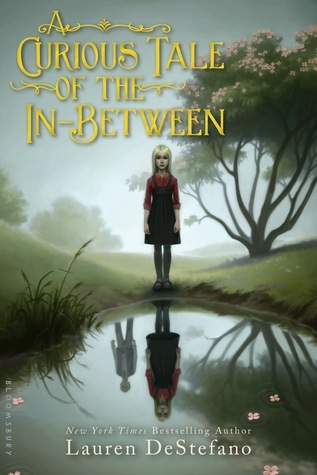 cover image has girl in pinafore and red shirt under it standing by edge of pond in middle of garden with ghostly trees behind her and fog. still water of pond shows her upside down reflection and boy behind her. large yellow letters at left top reads A Curious tale of the In-Between. small while ones at bottom reads Lauren DeStefano.