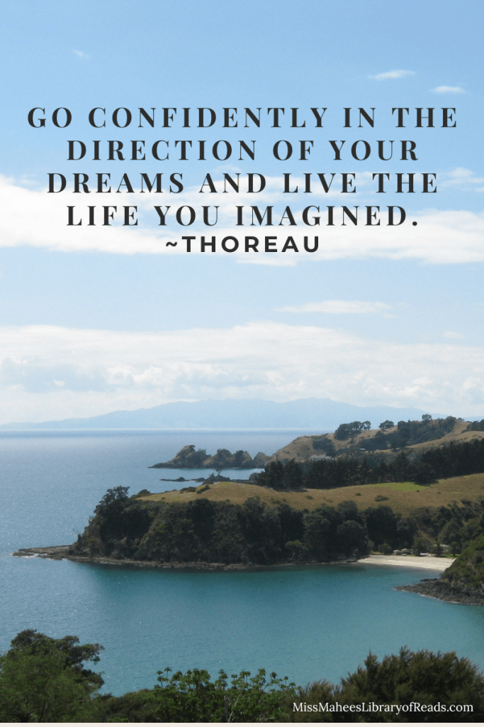 photo image of landscape with sea on left and blue/grey island at horizon in middle. small hills of green grass and trees jut out to sea and small patch of beach in lower right. white wispy clouds in blue sky at top. black letters all in capitals in sky is quote that reads 'Go Confidently in the direction of your dreams and live the life you imagined. - Thoreau'